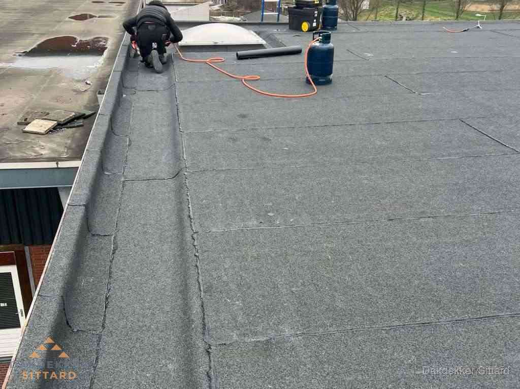 Dakdekker repareert bitumen dakbedekking op groot plat dak in Sittard